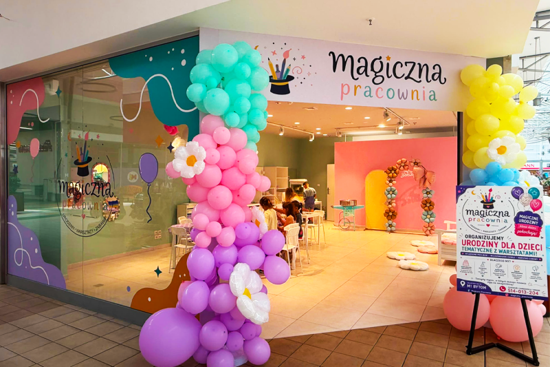 Otwarcie magicznej pracowni w M1 Bytom. Lokal magiczna pracownia, kolorowe balony i plakat promujący otwarcie.
